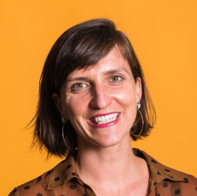 a smiling person in a polka dot shirt against an orange background